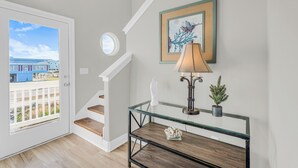 Eine Treppe führt zu einem Balkon mit Blick auf Gebäude, ein Glastisch mit Lampe und ein gerahmtes Kunstwerk an der Wand.
