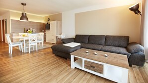 Ein modernes Wohnzimmer mit grauem Sofa, einem Holztisch und einem Essbereich mit weißen Stühlen und einem Tisch.