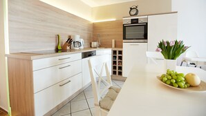 Eine moderne Küche mit Holzschränken, einem eingebauten Backofen und einem Essbereich mit weißem Tisch und Stühlen.