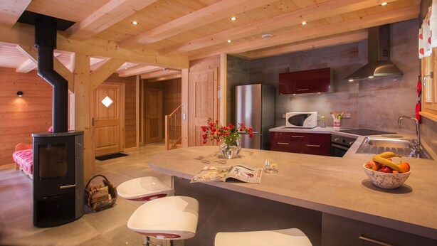 Une cuisine moderne dotée d’un îlot central, de poutres en bois, d’une cuisinière encastrée et d’un four à micro-ondes.