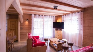 Une pièce chaleureuse avec des murs et un plafond en bois, un canapé en bois, une petite table et un téléviseur.