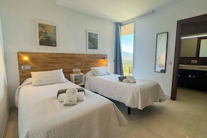 A hotel room with two beds, a wooden headboard, a large mirror, and artwork on the walls. - VillaTierra. Luxury villa. Best Views in Nerja (Nerja)