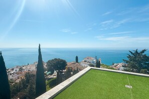 Une vue sur la côte, avec une zone herbeuse et des bâtiments en arrière-plan.