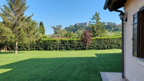Une pelouse bien entretenue, agrémentée d’une haie et d’arbres, un bâtiment doté d’une fenêtre et d’une porte, et, au loin, une structure qui ressemble à un château.