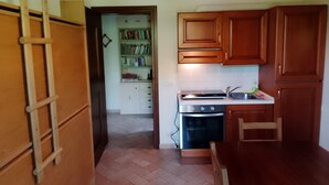 Une cuisine avec des meubles de rangement en bois, une cuisinière et une bibliothèque en arrière-plan.