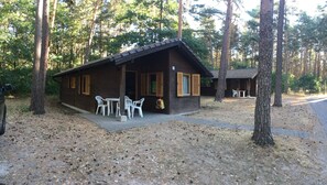 A rustic cabin with a porch, outdoor seating, and a small table.