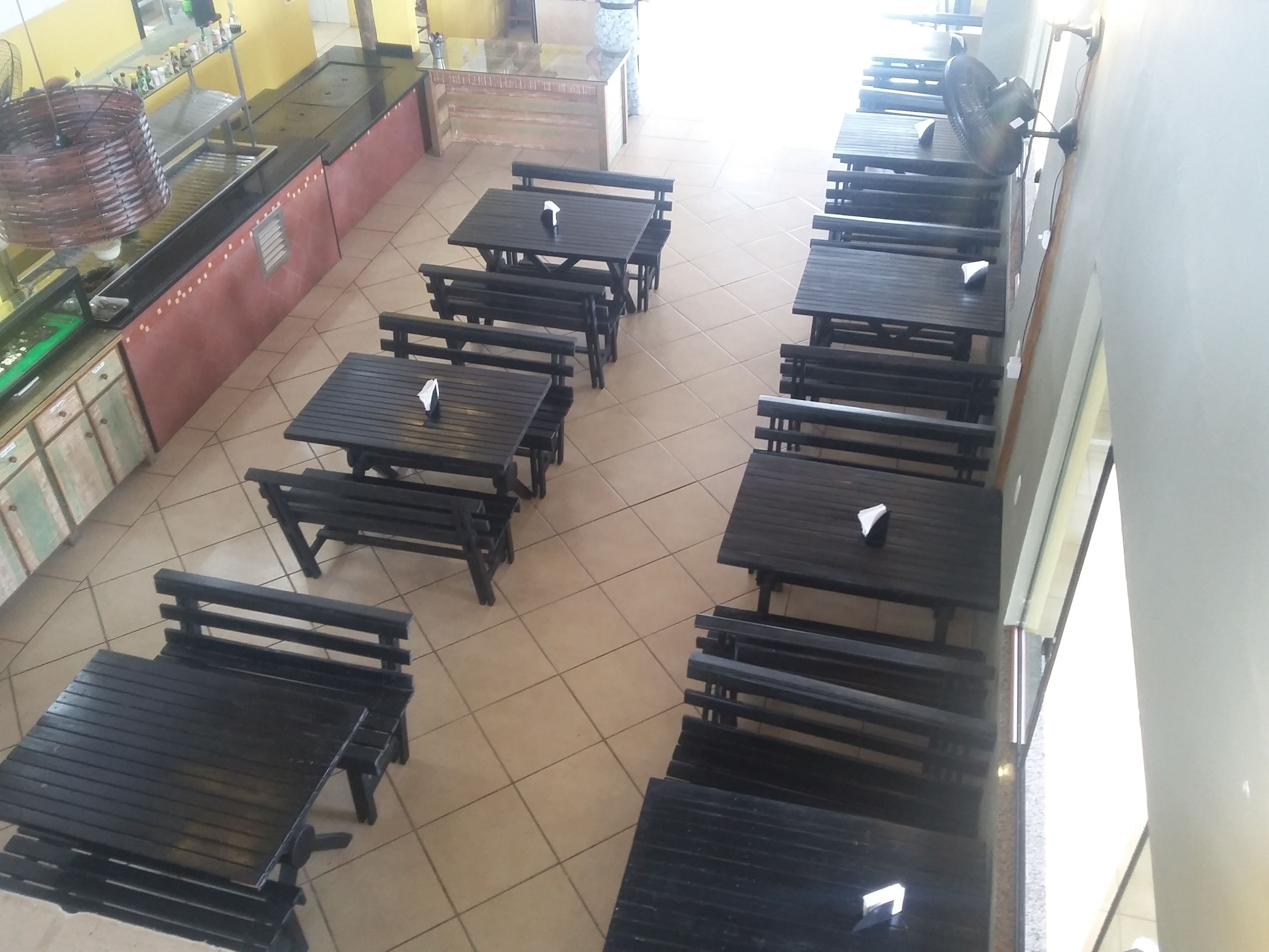 Un restaurant avec plusieurs tables en bois noir et un sol carrelé.