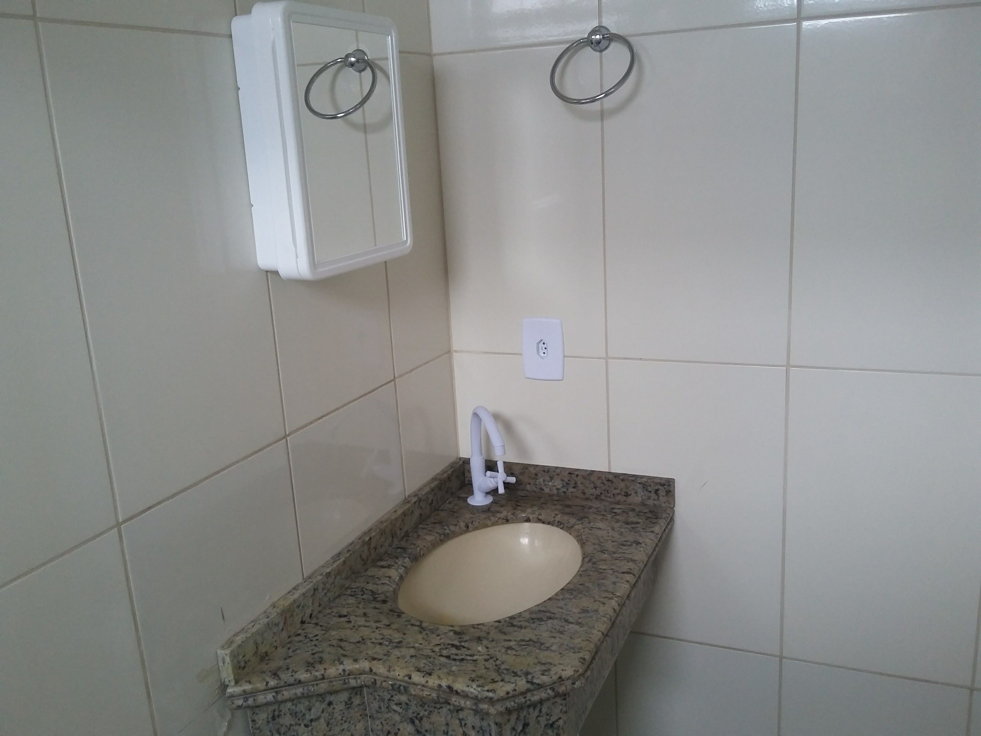 A bathroom with a granite countertop sink, a white cabinet, and a ring light fixture.