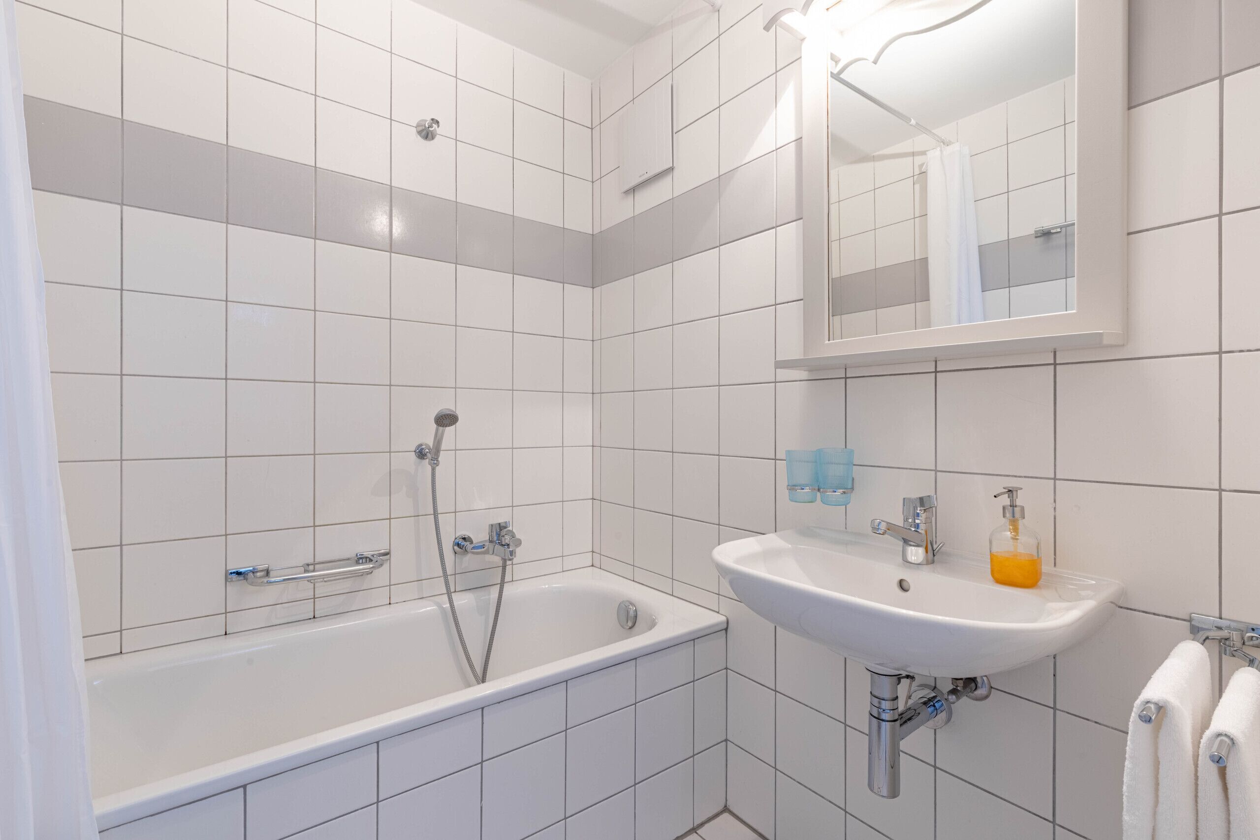 Un baño moderno con bañera, lavamanos y espejo.