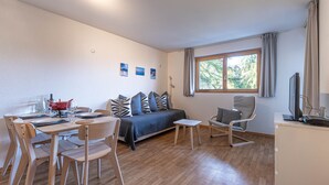 A modern, well-lit room with a wooden floor, a bed with a blue bedspread, a dining table with chairs, a small side table, and a window with curtains. - Pracondu 2 304 - OUTDOOR & FUN  apartment 6 pers (Haute-Nendaz)