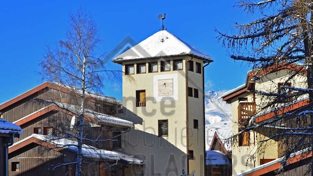 Um edifício coberto de neve com um relógio e uma placa indicando restaurante.