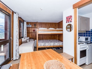 A compact room with a bunk bed, a small kitchenette, a wooden table, and a view through a large window. - Cozy Studio for 3 near Slopes & Shops, Balcony, Valley View - Montchavin La Plagne (Bellentre)