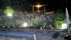 Ein gut beleuchteter Außenbereich mit einer Steinmauer, Sitzgelegenheiten und einer Pergola.