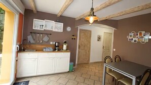 Eine Küche mit weißen Schränken, einer Holzbalkendecke und einem Essbereich mit Tisch und Stühlen.