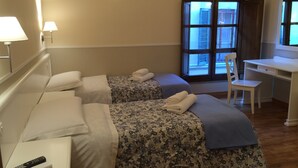 A hotel room with two beds, a desk, a chair, and a window with blinds. - Delightful studio apartment right in the center (Firenze)