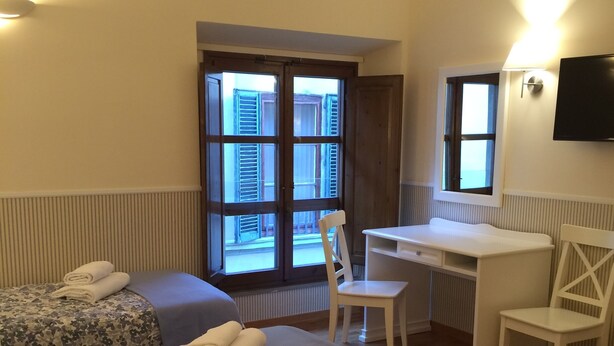 A hotel room with two beds, a desk, and a chair. - Delightful studio apartment right in the center (Firenze)
