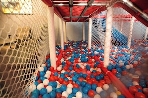 A play area with a netted enclosure, filled with multicolored balls, and a red canopy overhead. - Capital O 91202 Wow Hotel (George Town)