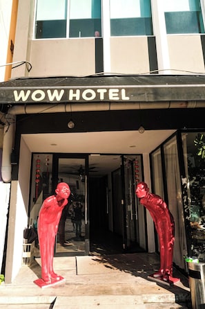 A hotel entrance with a sign reading 'WOW HOTEL,' two red statues in front, and a clear view into the building. - Capital O 91202 Wow Hotel (George Town)