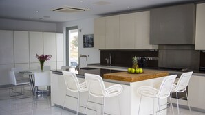 Una cucina moderna con sgabelli da bar bianchi, un'isola in legno ed elettrodomestici in acciaio inossidabile.