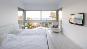 Una camera da letto moderna con un letto grande, una poltrona bianca e un televisore a parete.