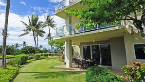 A modern two-story building with a balcony, surrounded by lush greenery and palm trees. - Beautiful Vista Waikoloa B105 - Renovated in 2018! (Waikoloa)