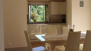 Una cucina con finestra, mobili bianchi e un tavolo da pranzo con sedie.