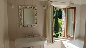 Un bagno con lavandino, specchio e finestra con tende.