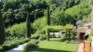 Un giardino curato con un vialetto in ghiaia, una zona verdeggiante e un pergolato in legno.