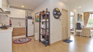 Een ruimtelijk ingerichte leefruimte met een kitchenette, een ingebouwde boekenkast en een zithoek met uitzicht.