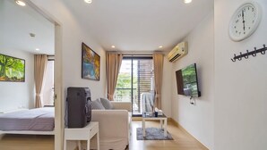 Een moderne hotelkamer met een bed, een bureau met koffiezetapparaat, een televisie en een raam met luxaflex.