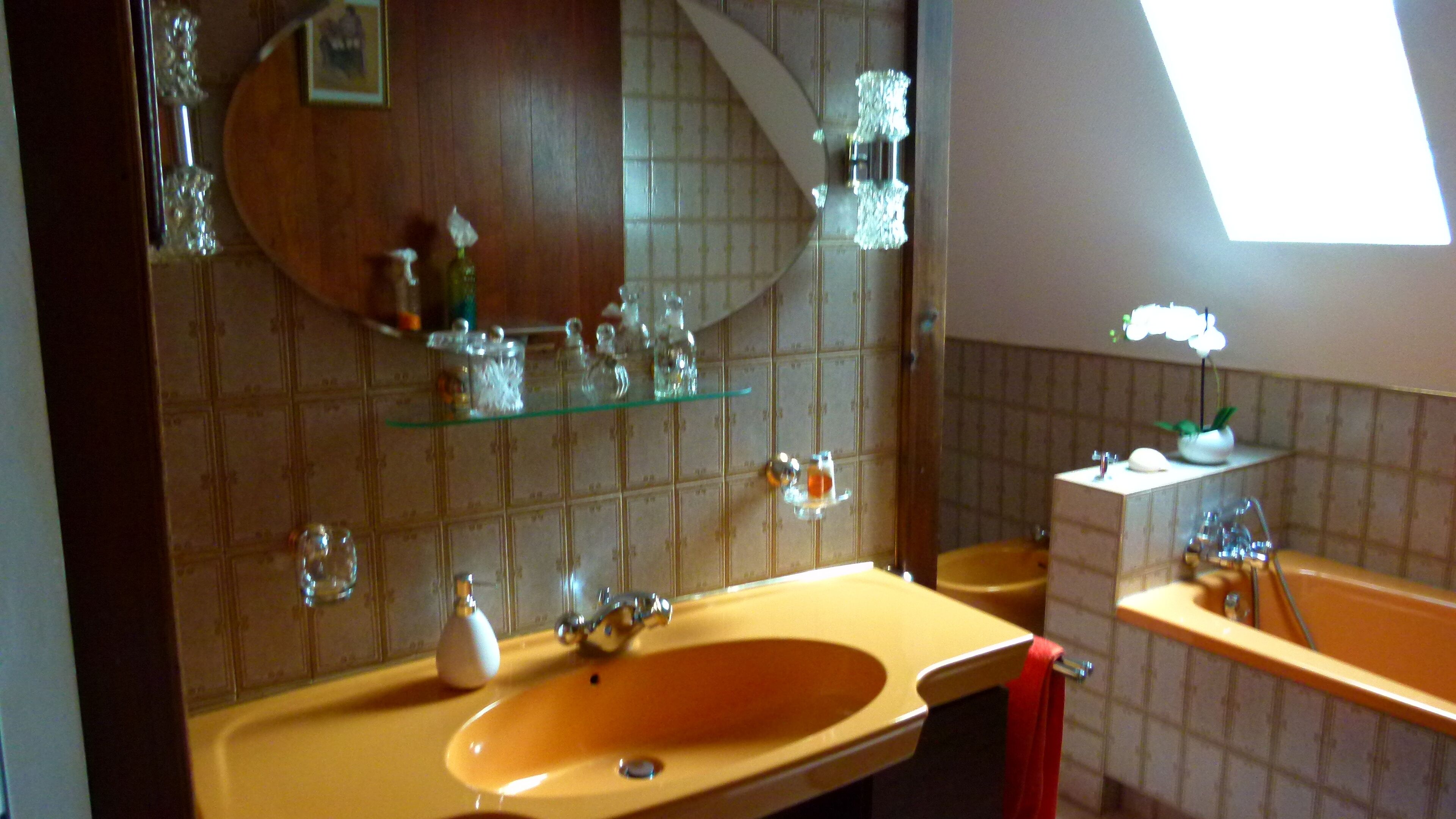Ein Badezimmer mit einem großen, ovalen Waschbecken, einem Spiegel und einem Fenster, das für natürliches Licht sorgt.