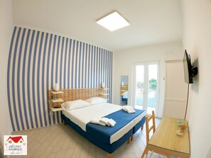 Une chambre à coucher avec un lit, des tables de chevet, une télévision et une vue sur l’extérieur.