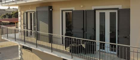 Un edificio residencial con balcón, entrada protegida por un portón y un logo que indica que es propiedad de Antonio & Maria.