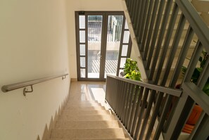 A staircase with a metal handrail, leading to a glass door with a view of the outside.