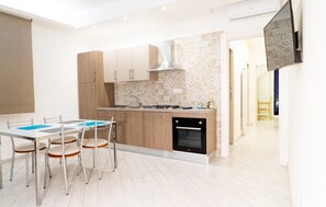 A modern kitchen with a dining area, featuring a kitchen island, wooden cabinets, and a built-in oven.