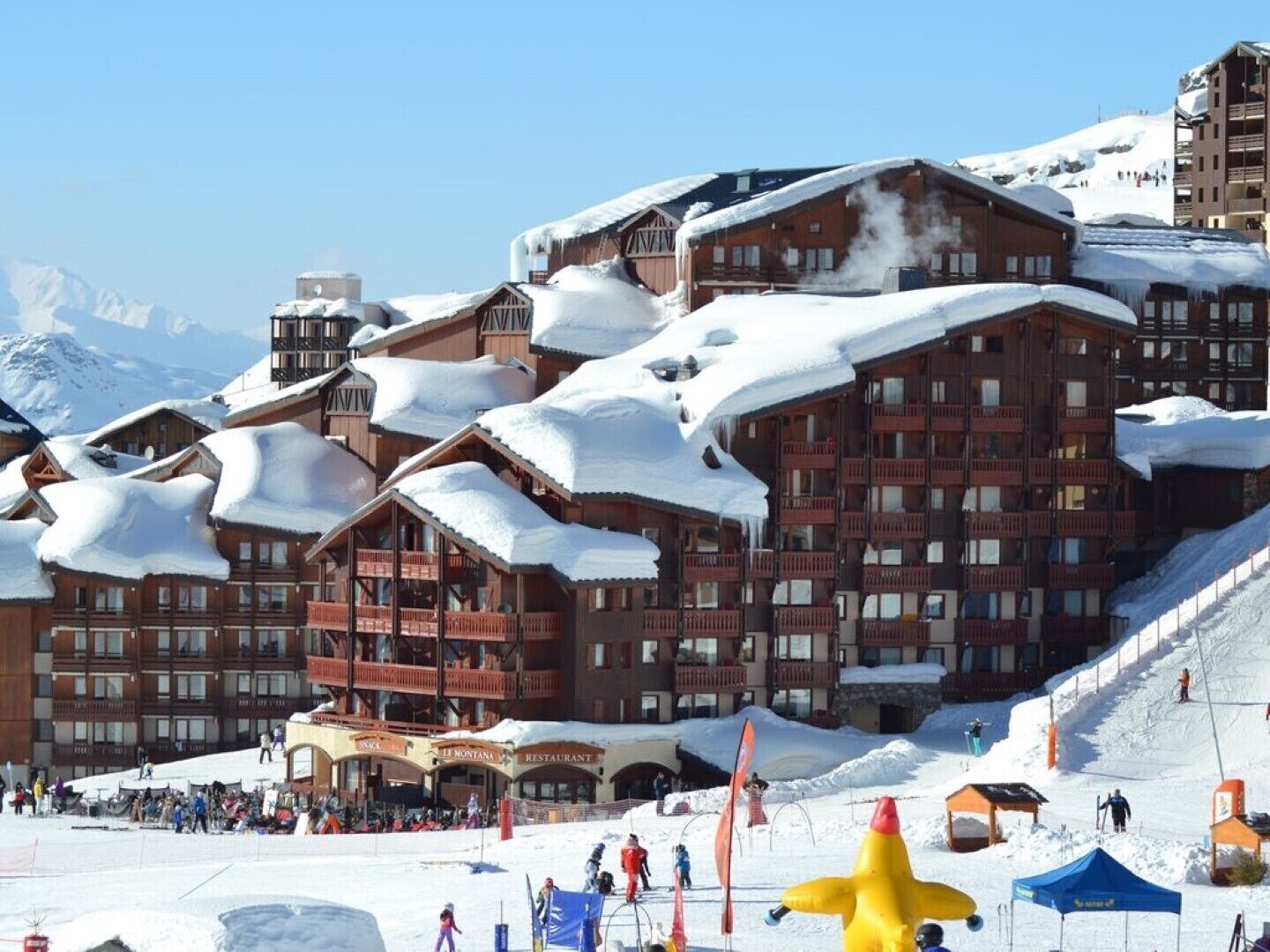 A ski resort with wooden buildings, ski slopes, and a snow-covered landscape.