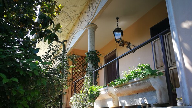 Een stenen trap die leidt naar een balkon met planten en een hanglamp.