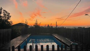 Una piscina rectangular rodeada por una terraza y una valla de madera.