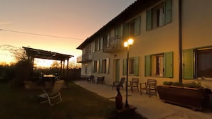 Un edificio de dos pisos con balcón, zona de estar al aire libre y pérgola.