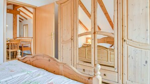 Une chambre à coucher avec un lit en bois, une armoire en bois et un miroir qui reflète l’intérieur de la pièce.