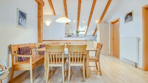 Un coin repas avec des meubles en bois, un luminaire suspendu et une vue sur la cuisine.