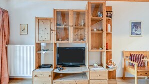 Un meuble de rangement en bois comprenant un téléviseur, des placards et une petite table avec un panier.