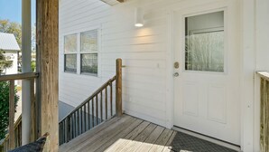 Une façade blanche avec un escalier en bois menant à une porte.