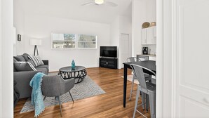 Un salon moderne comprenant un canapé, un téléviseur, une table à manger et des chaises.