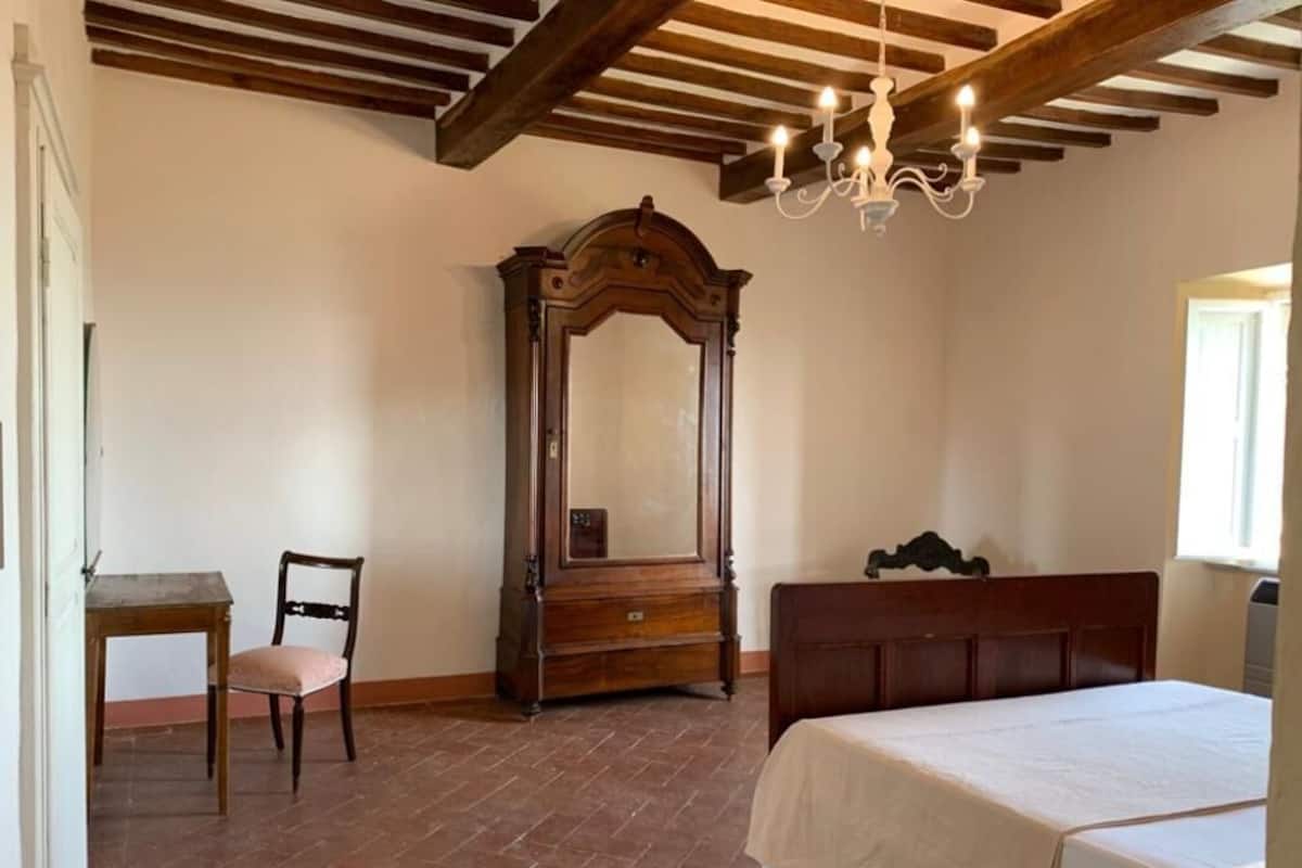 Une chambre à coucher avec un lit en bois, une table de chevet, une commode, une chaise et un miroir.