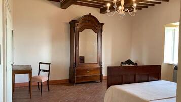 Ein Schlafzimmer mit einem Holzbett, einem Nachttisch, einer Kommode, einem Stuhl und einem Spiegel.