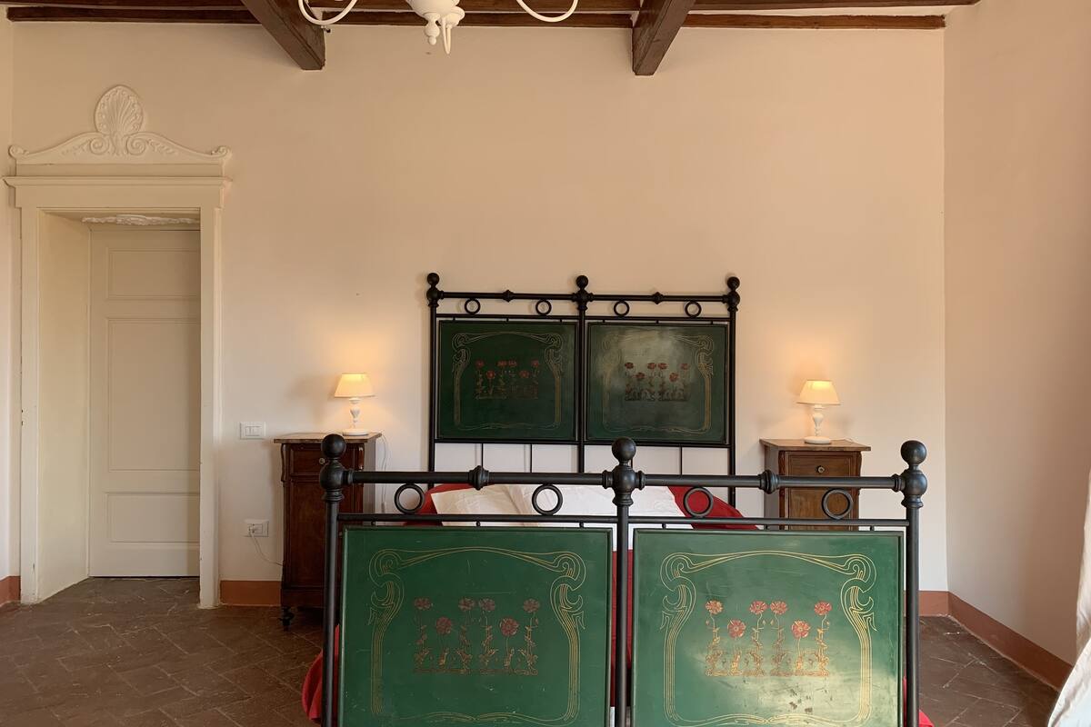 Une chambre avec un lit, deux lampes de chevet, un lustre et une porte.