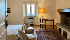 Una habitación acogedora con candelabro, chimenea, una mesa de comedor con lámpara y un tapete estampado.