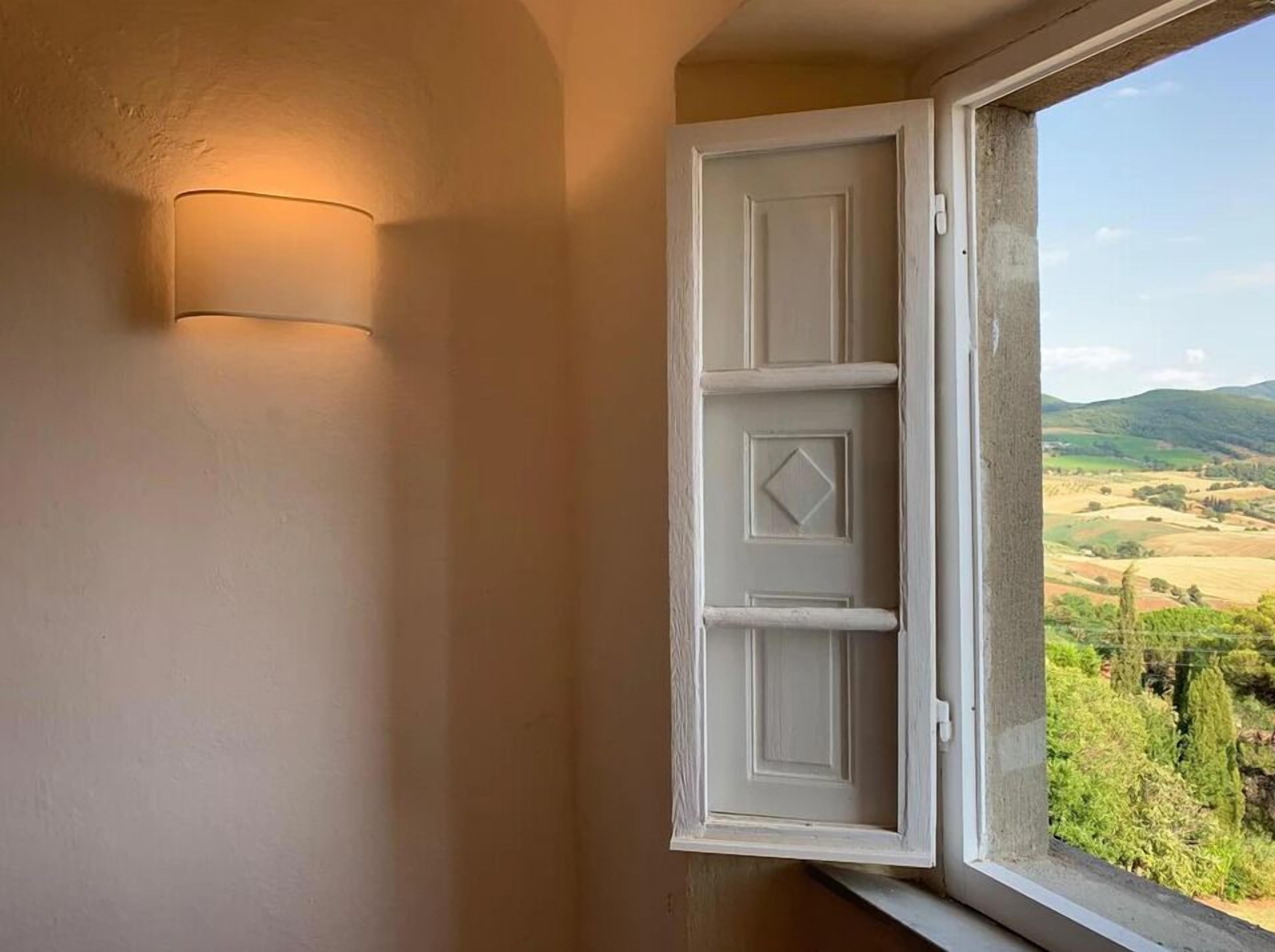 A room with a window, a white door, and a wall-mounted light fixture.