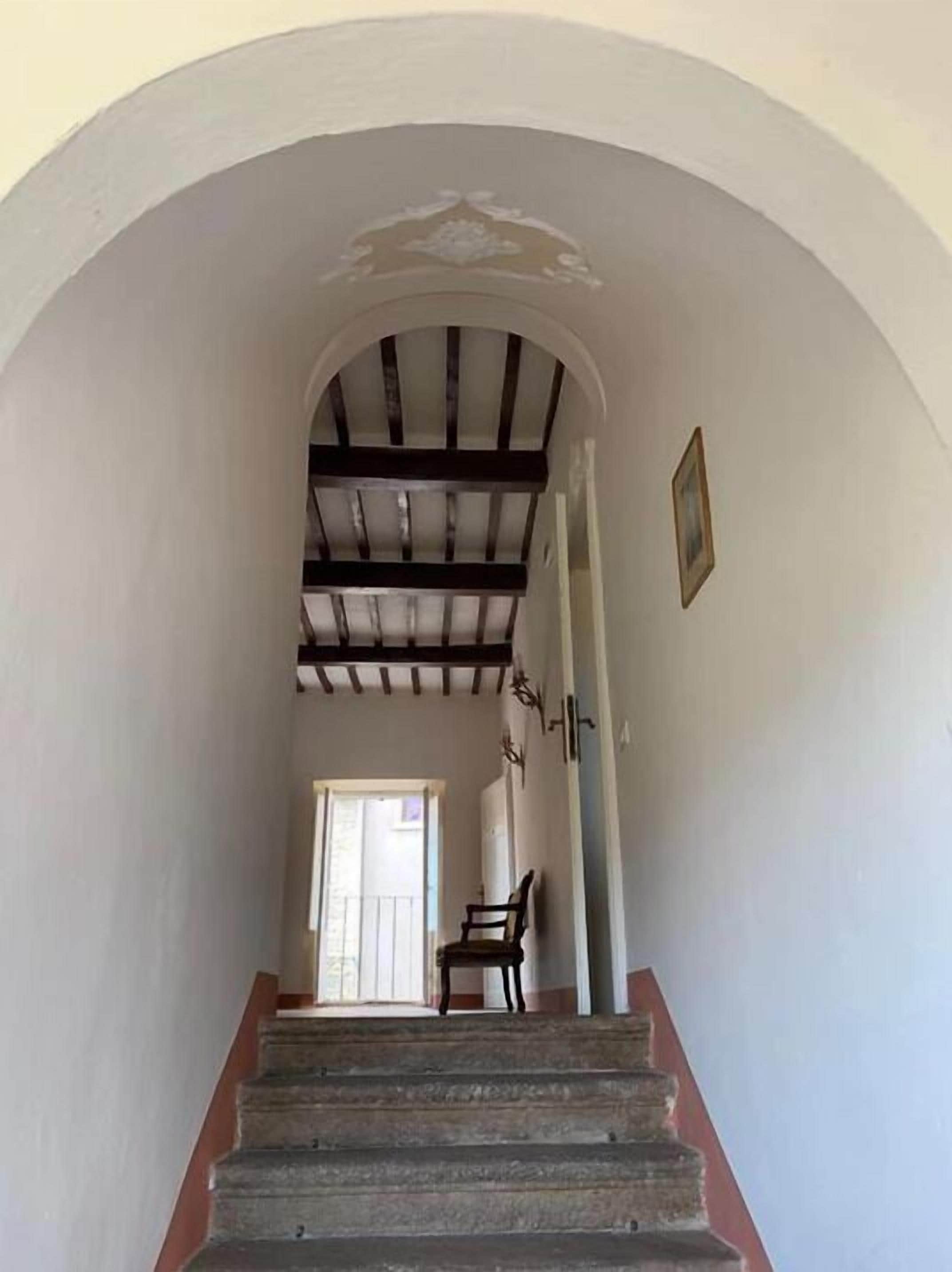 Una escalera con barandilla de madera y una silla al pie.
